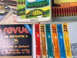 several books are stacked on a table with a train in the background