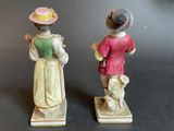 pair of figurines of a woman and a man with hats on