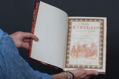 un homme tenant un livre ouvert sur lequel figure une illustration
