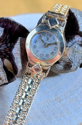 a silver watch sitting on top of a silver bracelet