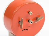a red clock that has a sad face on it