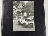 an old black and white photo of a man driving a race car