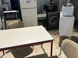plusieurs chaises et une table dans une pièce, avec un réfrigérateur à l'arrière-plan