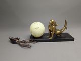 une statue représentant une sirène et une boule posée sur un socle