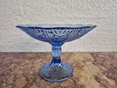 un bol en verre bleu posé sur une table, avec un mur blanc en arrière-plan