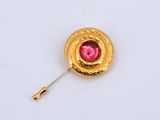 an image of a gold brooch with a pink stone in the center