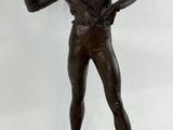 bronze statue of a man holding a knife and standing on a wooden platform
