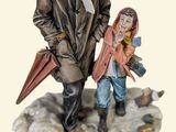 figurine of a man and a woman holding umbrellas on a table