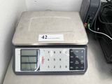 a digital scale sitting on top of a counter next to a printer