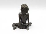 bronze statue of a woman sitting on the ground with her legs crossed