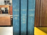 three blue books sitting on top of a wooden table next to a yellow bench