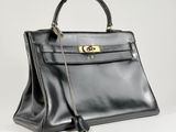 a black leather handbag with gold hardware on the handle