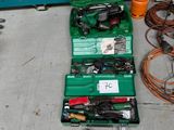 une mallette à outils verte posée par terre, contenant des outils