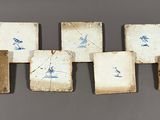 Plusieurs carreaux ornés de motifs bleus et blancs sont disposés en rangée