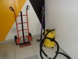 a vacuum and a hand truck in the corner of a room