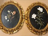 Deux tableaux représentant des fleurs, encadrés, sont accrochés côte à côte sur un mur.