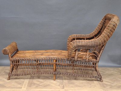 une chaise longue en osier posée sur le parquet