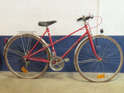 un vélo rouge appuyé contre un mur bleu et blanc