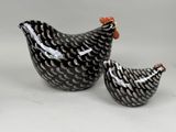 deux poulets en céramique, l'un noir et l'autre blanc, assis l'un à côté de l'autre