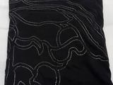 black t - shirt with white embroidery on it sitting on a white surface
