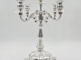a silver candelier with three candles on a white background