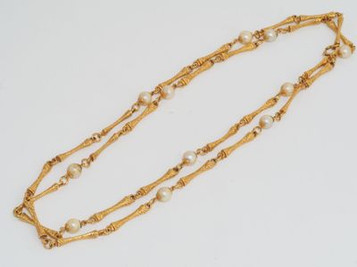 a close up of a gold necklace with pearls on a white background