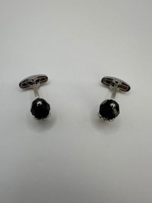 une paire de boutons de manchette noirs et blancs posés sur une surface blanche