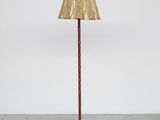 a red floor lamp with a bamboo shade on top of it