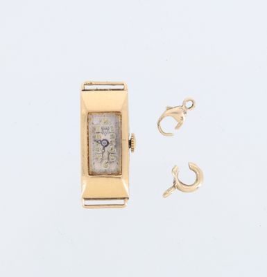 une montre en or et une paire de boucles d'oreilles posées sur une surface blanche