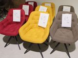 plusieurs chaises de différentes couleurs, munies d'étiquettes de prix, disposées dans une pièce