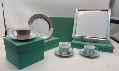 deux tasses et soucoupes posées sur une table, à côté d'un cadre photo