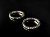 two gold rings with diamonds on a black background