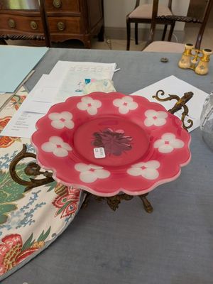 une assiette rose ornée de fleurs blanches, posée sur une table