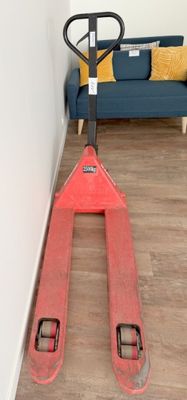 un chariot élévateur rouge posé dans un coin du salon