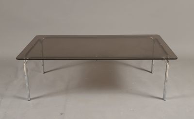 une photo d'une table basse avec un plateau en verre et des pieds chromés