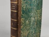an old book with a green cover sitting on a table
