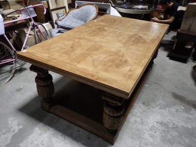 une grande table en bois avec un piètement en bois, placée au milieu d'une pièce