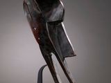 a wooden mask on a stand against a gray background