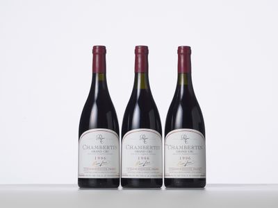 three bottles of red wine are lined up on a table