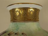 a green vase with a gold rim and a picture on it