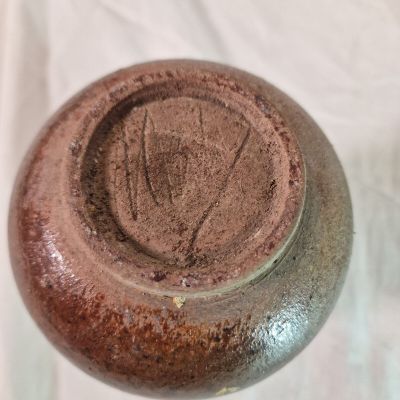 un gros plan d'un vase marron posé sur une surface blanche