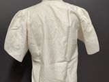 a white shirt on a mannequin stand against a black wall