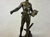 bronze statue of a man holding a book and a sword