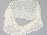 a close up of a white lace shawl on a gray surface