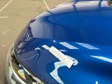 a blue car parked in a parking lot with a sticker on it ' s hood