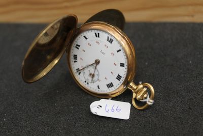 une montre de poche en or posée sur une table, à laquelle est attachée une étiquette