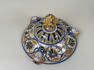 un saladier bleu et jaune avec un couvercle, posé sur une table blanche