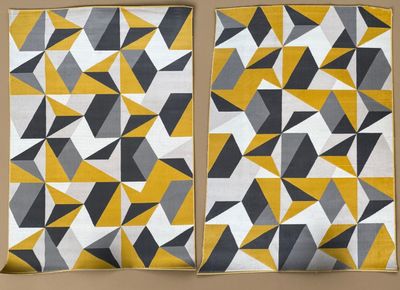 deux morceaux de tissu à motifs jaunes et gris accrochés à un mur