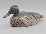 un canard en bois posé sur une surface blanche
