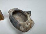 a small piece of pottery sitting next to a small piece of wood